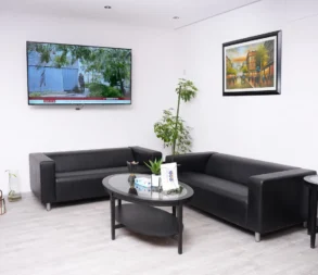 Contemporary office lounge with black sofas, TV, and artwork in Riyadh.
