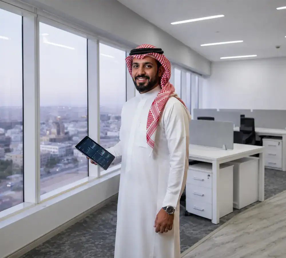 Businessman in traditional Saudi attire in modern office with city view.